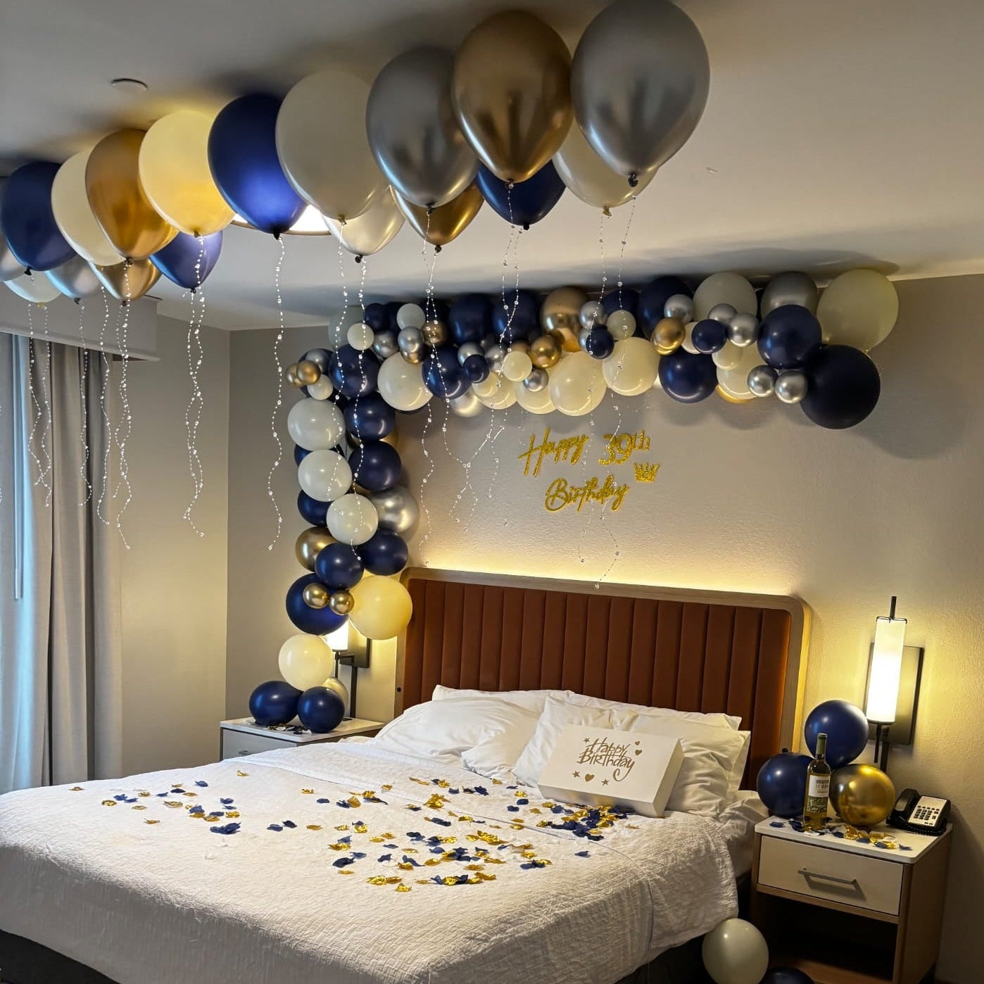 Decorated bedroom with balloons and 'Happy 39th Birthday' sign above a bed.